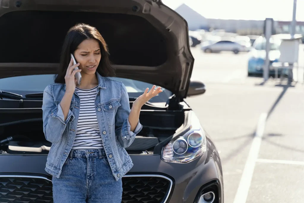 Woman on phone next to broken down car